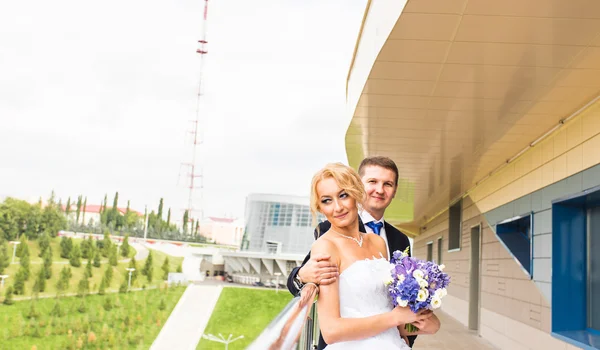 Hochzeitspaar umarmt, die Braut hält einen Blumenstrauß, der Bräutigam umarmt sie im Freien — Stockfoto