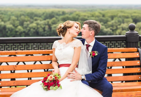 Bruidspaar knuffelen, het houden van een boeket bloemen, bruid bruidegom omarmen haar buitenshuis — Stockfoto