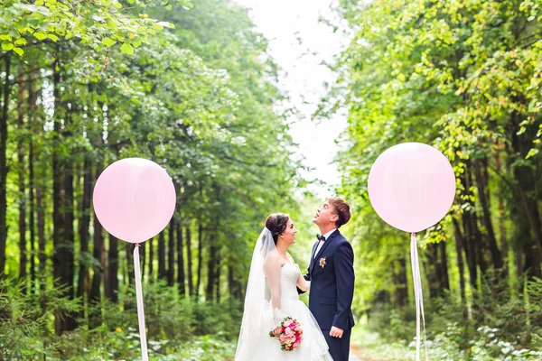 Весілля пара обіймає, наречена тримає букет квітів, наречений обіймає її на відкритому повітрі — стокове фото