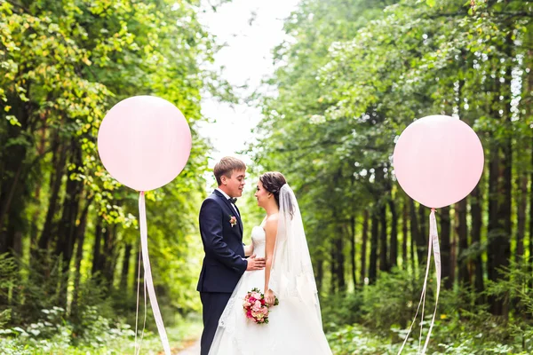 Couple de mariage câlin, la mariée tenant un bouquet de fleurs, marié embrassant son plein air — Photo