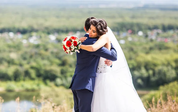 Bela noiva e noivo abraçando em seu dia de casamento ao ar livre — Fotografia de Stock