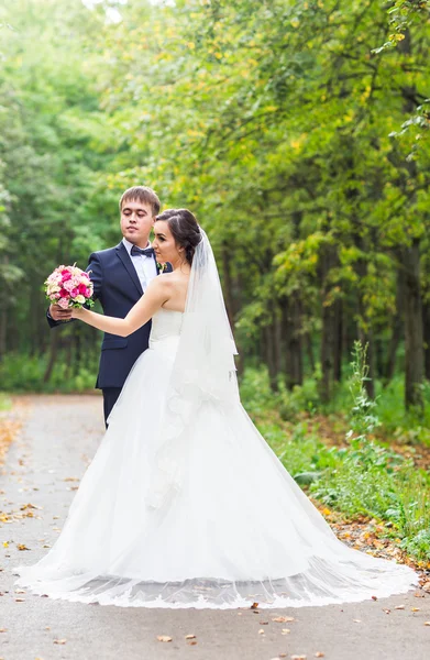 Жених и невеста на свадьбе прогулка на свежем воздухе. Счастливые молодожены обнимаются. Любящая пара . — стоковое фото