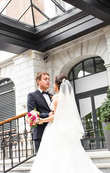 Onu açık havada kucaklayan Düğün çifti, sarılma bir buket çiçek, holding gelin damat