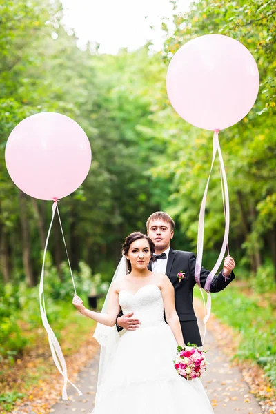 Onu açık havada kucaklayan Düğün çifti, sarılma bir buket çiçek, holding gelin damat