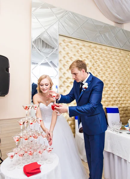 A menyasszony és a vőlegény pezsgőt öntenek az üvegbe.. — Stock Fotó