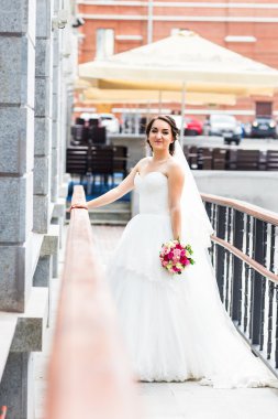 Gelinlikli genç gelin elinde buket tutuyor.