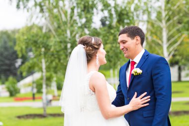 Onu açık havada kucaklayan Düğün çifti, sarılma bir buket çiçek, holding gelin damat