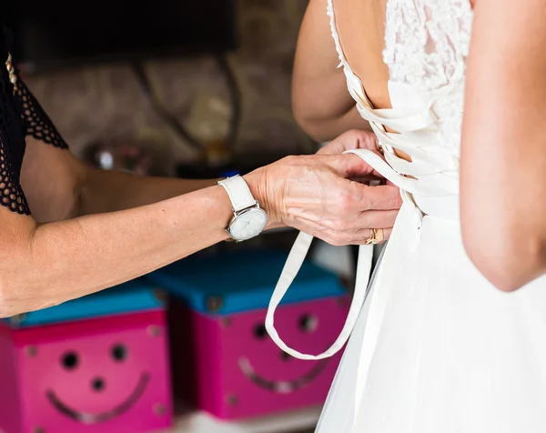 Bridesmaid is helping the bride to dress — Stock Photo, Image