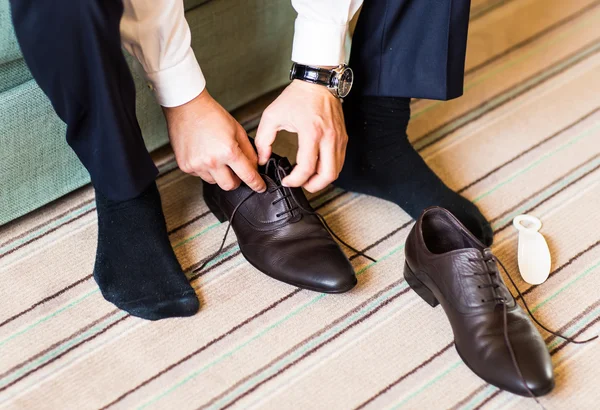 Крупный план молодой человек завязывает элегантную обувь в помещении — стоковое фото