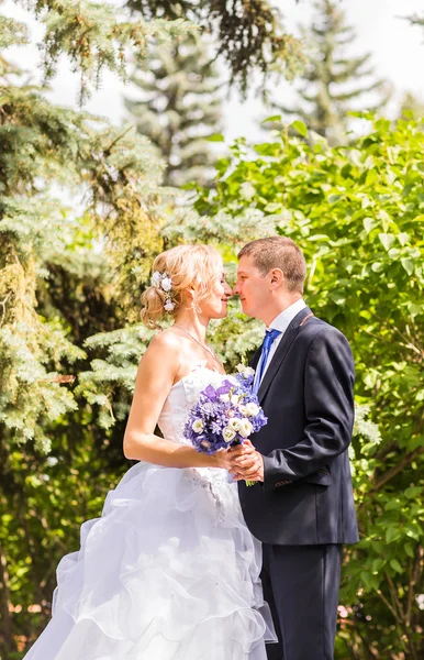 Mariée et marié le jour du mariage marchant à l'extérieur. Heureux jeunes mariés embrassant. Couple aimant . — Photo