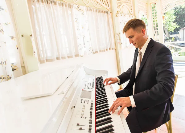 Brudgummen spelar på ett piano i rummet — Stockfoto
