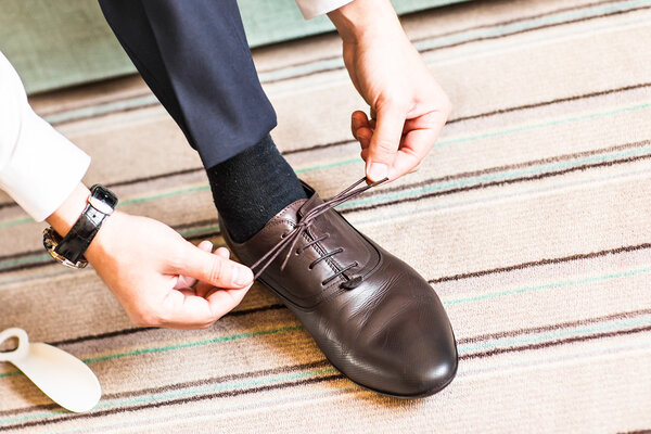 Close-up young man tying elegant shoes indoors