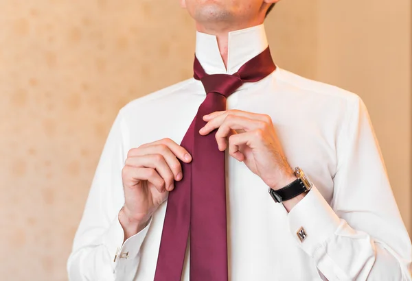 Portrait of  handsome businessman in suit putting on necktie indoors close-up — Stock Photo, Image