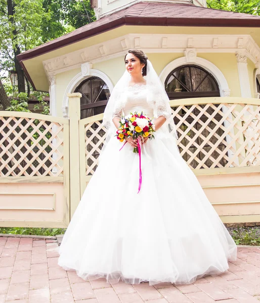 Красива наречена з весільним букетом квітів на відкритому повітрі в парку . — стокове фото
