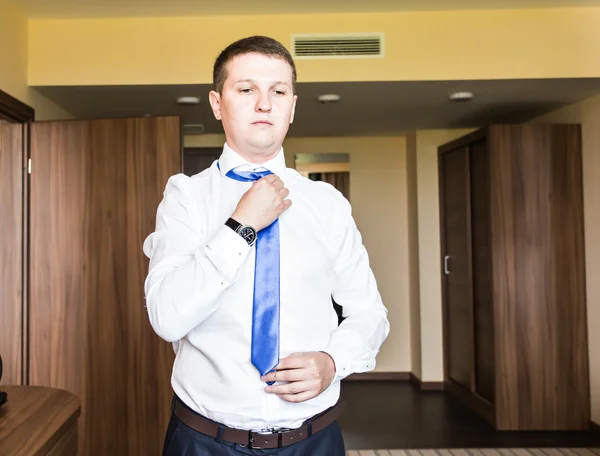 Portrait of  handsome businessman in suit putting on necktie indoors — Stock Photo, Image