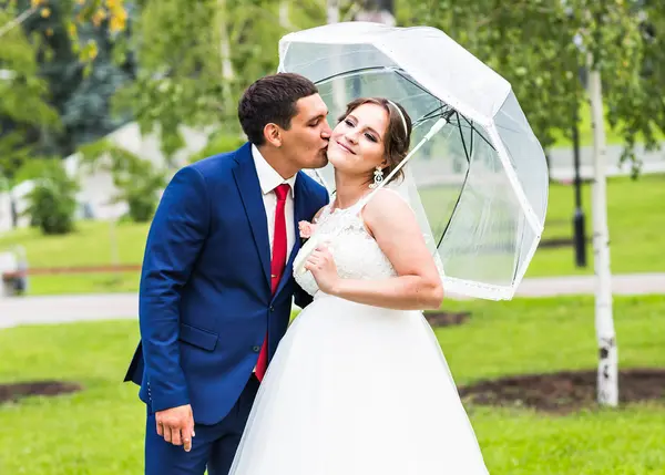 Novia y novio en el día de la boda caminando al aire libre. Recién casados felices abrazándose. Pareja amorosa . — Foto de Stock