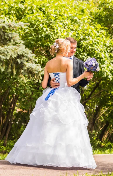 Noiva e noivo no dia do casamento andando ao ar livre. Feliz abraço dos recém-casados. Casal amoroso . — Fotografia de Stock