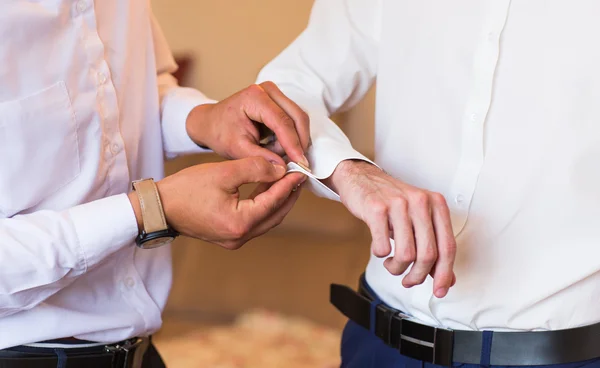 Groomsman helps  groom to put on cufflinks close up — Stock Photo, Image