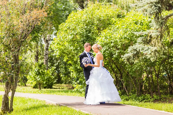 Mooie bruid en bruidegom omarmen op hun trouwdag buitenshuis — Stockfoto