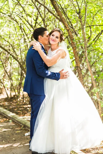 Hermosa novia y novio abrazando en su boda al aire libre — Foto de Stock