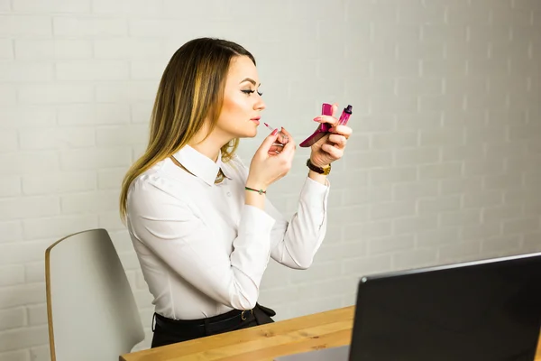 Mujer de negocios mirándose en el espejo y usando lápiz labial en su mundo —  Fotos de Stock