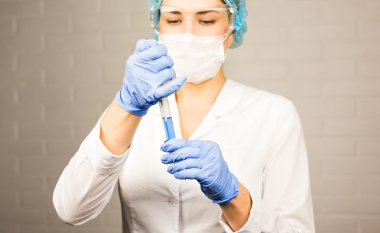 Bilim, kimya, biyoloji, tıp ve insanlar kavramı - klinik laboratuvar araştırma yapma tüp bebek tutan genç kadın bilim adamı yakın.