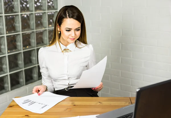 Concept d'entreprise - femme d'affaires assise sur le lieu de travail et le papier de lecture au bureau — Photo