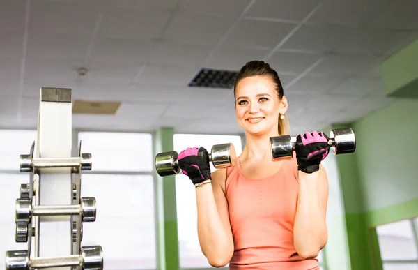 Sport, fitness, bodybuilding, lagarbete och människor koncept - ung kvinna flexar muskler på gymmet maskin — Stockfoto