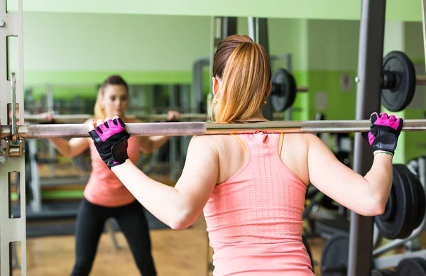 Sport, fitness, bodybuilding, lagarbete och människor koncept - ung kvinna flexar muskler på gymmet maskin — Stockfoto