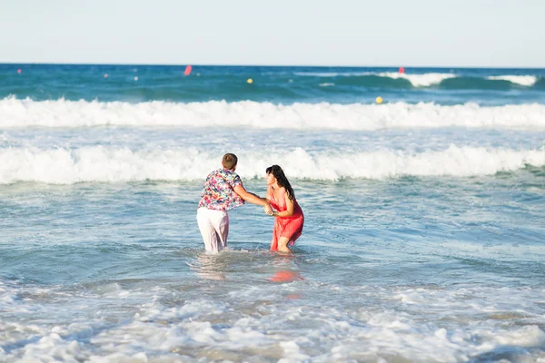 Szczęśliwa młoda para o zabawy, mężczyzna i kobieta w morze przy plaży. — Zdjęcie stockowe