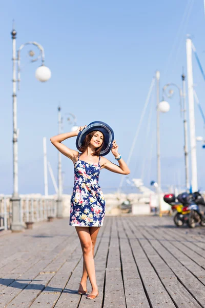 Podróżować pojęcie turystyki i ludzi. Młoda kobieta z kapelusz stojący w pobliżu łodzi w marinie — Zdjęcie stockowe