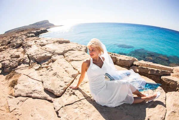 Jovem mulher sentada em uma rocha perto da praia — Fotografia de Stock