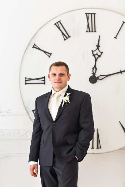 Man in black suit with big clock on background, time concept