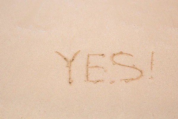 Sí - escrito en arena sobre textura de playa — Foto de Stock