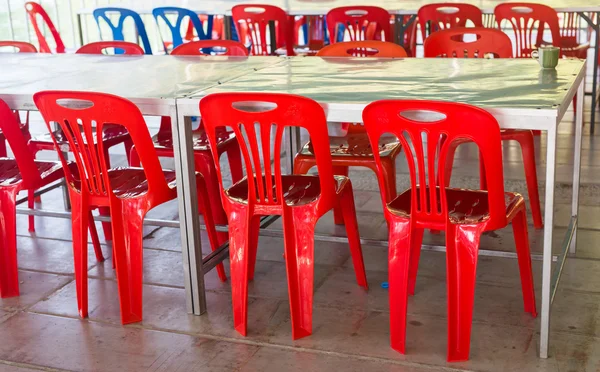 Интерьер столовой с цветными пластиковыми стульями и столами — стоковое фото