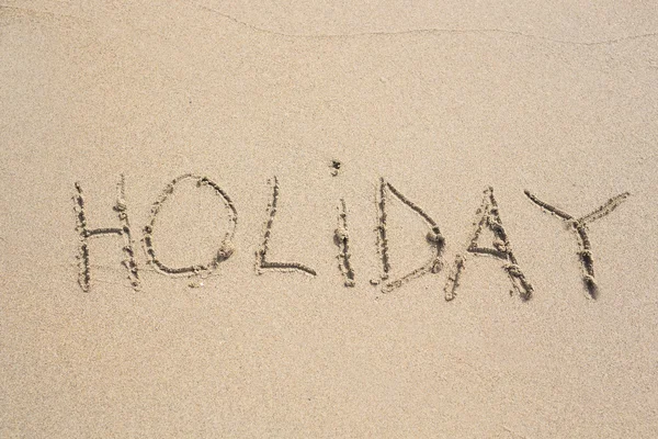Het woord vakantie in het zand. — Stockfoto