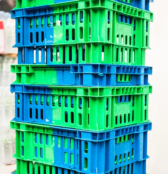 Stapel von Kunststoffpaletten in blauer und grauer Farbe neben einem Geschäft gestapelt. — Stockfoto