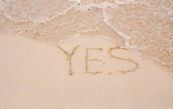 Ja - geschreven in het zand op het strand textuur — Stockfoto
