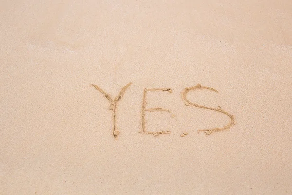 Sí - escrito en arena sobre textura de playa — Foto de Stock