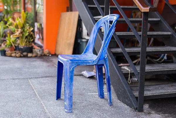 Грязное ретро повредило пластиковый синий стул на улице — стоковое фото