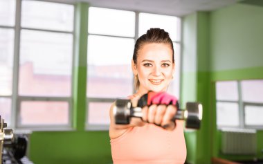 Dambıllarla egzersiz yapan kadın.