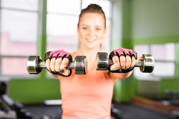 Concept de fitness, sport, entraînement et style de vie - femme heureuse avec haltères flexion des muscles dans la salle de gym — Photo