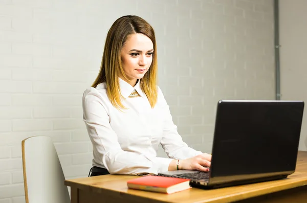 Portrait de belle jeune femme travaillant avec un ordinateur portable dans son bureau. — Photo