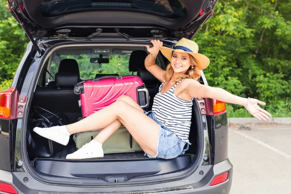 Junge attraktive Frau, die im offenen Kofferraum eines Autos sitzt. Sommer-Roadtrip — Stockfoto