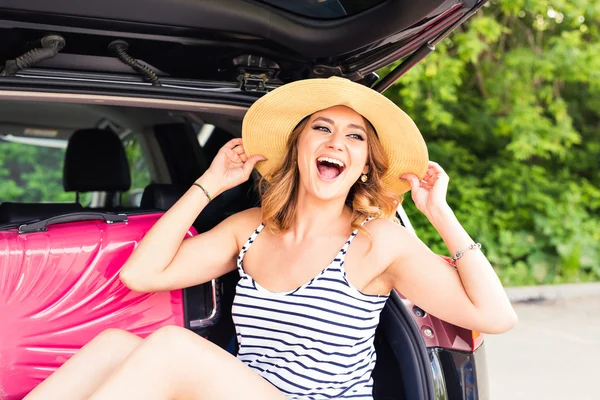 Junge attraktive Frau, die im offenen Kofferraum eines Autos sitzt. Sommer-Roadtrip — Stockfoto