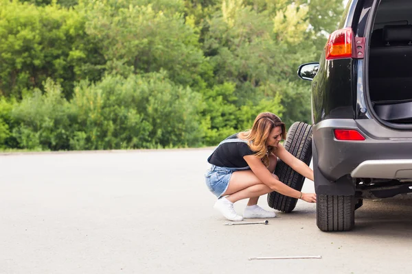 Woman changes the wheel of car on a road — Stock Photo, Image