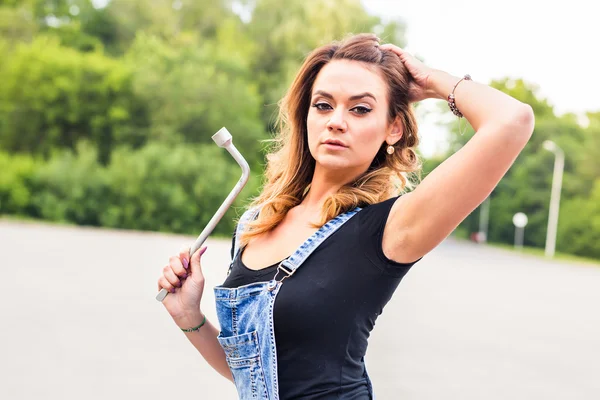 Hermosa mujer sexy en el traje de los trabajadores del cuidado que sostiene una herramienta para las reparaciones del coche —  Fotos de Stock