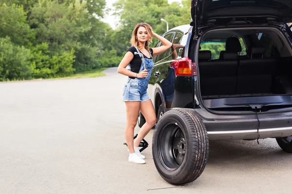 Mladá žena s rozpisem pneumatiky v autě — Stock fotografie