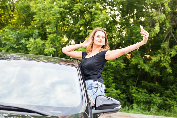 Lächelnde junge Frau macht Selfie-Foto mit Smartphone-Kamera im Auto — Stockfoto