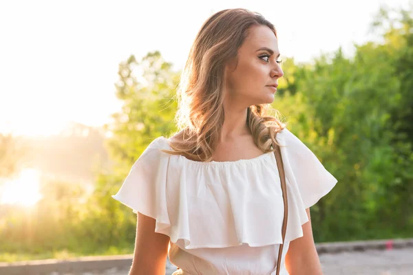 Aantrekkelijke jonge vrouw genieten van haar tijd buiten in park met zonsondergang in de achtergrond — Stockfoto